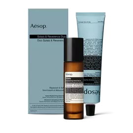 A pump bottle of Solais Replenishing Hand Serum and a tube of Reverence Aromatique Hand Balm together in a carboard box