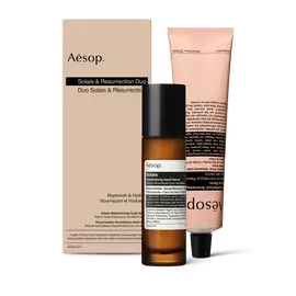 A pump bottle of Solais Replenishing Hand Serum and a tube of Resurrection Aromatique Hand Balm together in a carboard box.