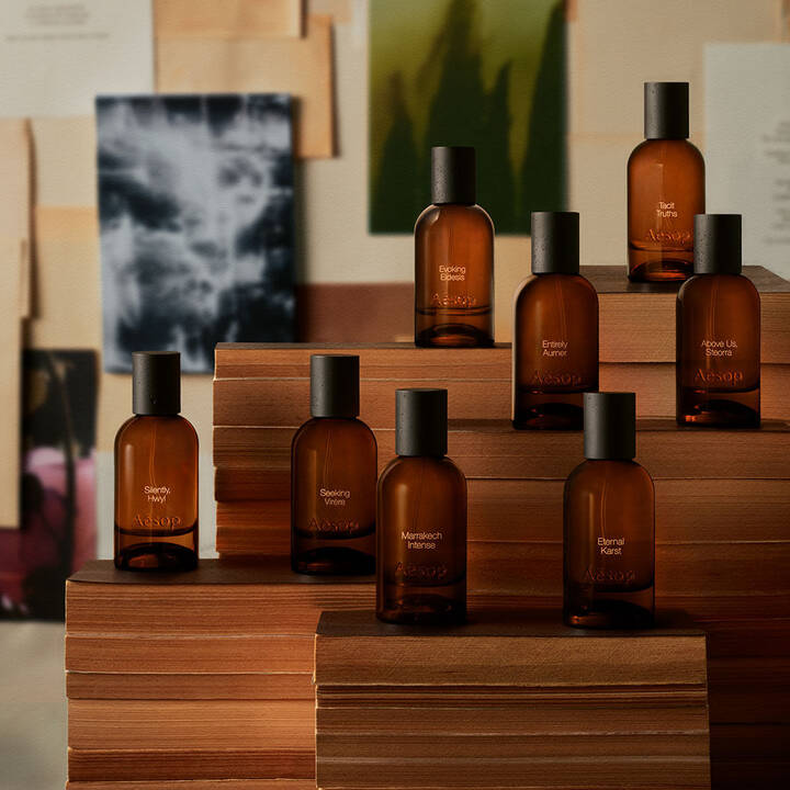 Aesop amber glass perfume bottles displayed on stacked books.